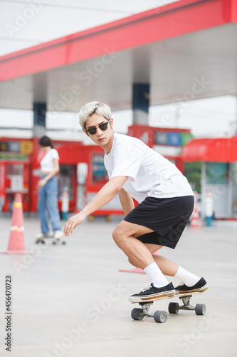 asian young man wear sunglasses playing skateboard on street city. skateboarding outdoor sports. extreme sports concept.