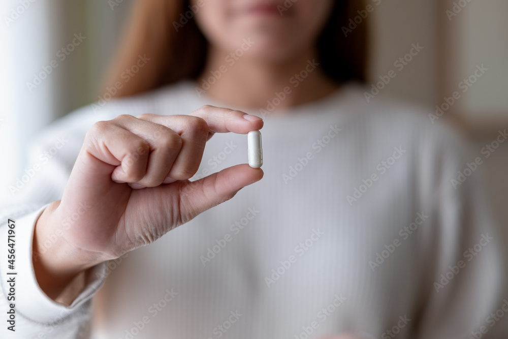 © Farknot Architect - A woman holding and showing white medicine capsules in hand © Farknot Architect - A woman holding and showing white medicine capsules in hand
