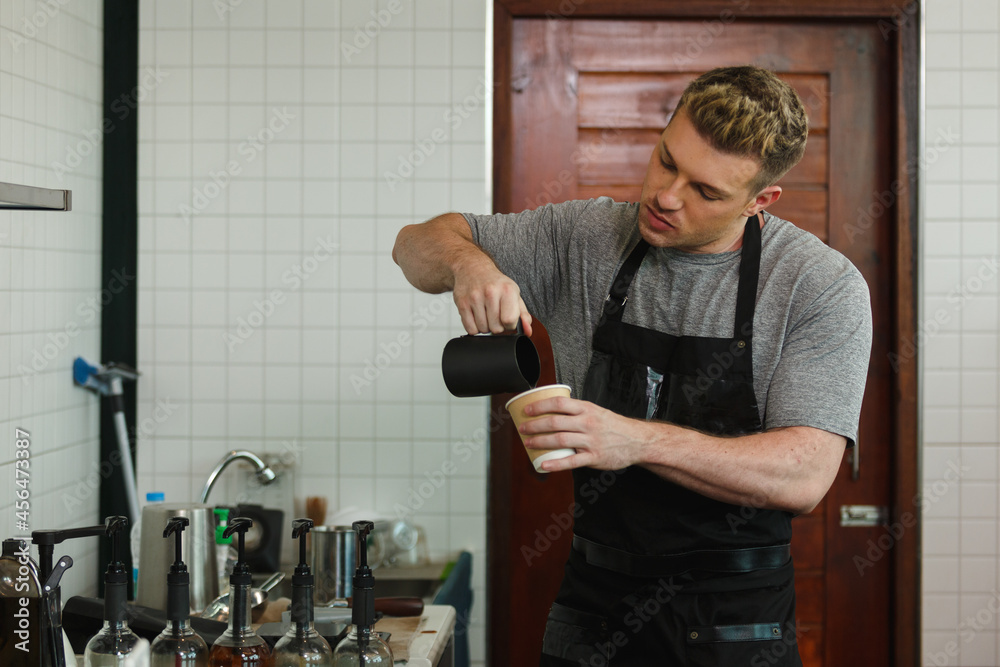 young man barista wear uniform working in coffee shop making coffee at counter bar cafe. professional coffee.