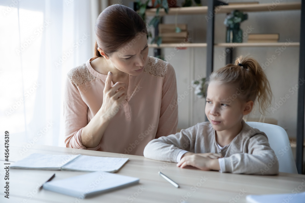 Unhappy young mother scolding lecture for stressed little child daughter for bad marks, doing homework together indoors. Frustrated depressed small girl having problems with study, education concept. Unhappy young mother scolding lecture for stressed little child daughter for bad marks, doing homework together indoors. Frustrated depressed small girl having problems with study, education concept.