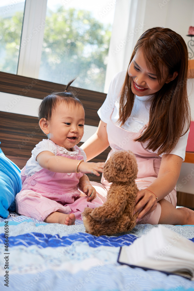 Happy little girl excited to play with new stuffed toy mother is giving her Happy little girl excited to play with new stuffed toy mother is giving her