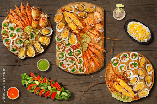 Lobster Thermidor, grilled lobster , scallops, grilled oysters and mussels with cheese, grill cuttlefish, scallops in wooden plate with lime. Isolated on wooden background. Menu baner photo