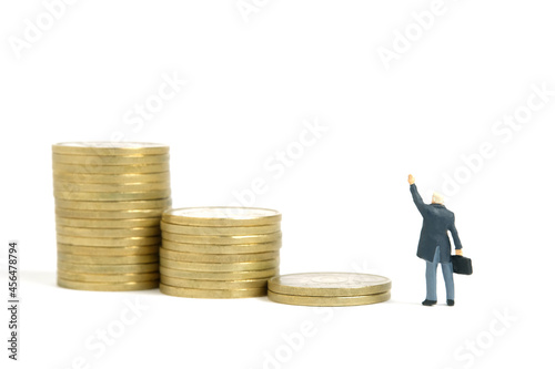 Miniature people toy figure photography. Financial freedom plan concept. A businessman standing in front of coin money pile stair while raise his hand. Isolated on white background