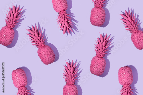 Creative pattern with bright pink painted pineapple on pastel purple background. Fruit art concept. Minimal food colorful idea.