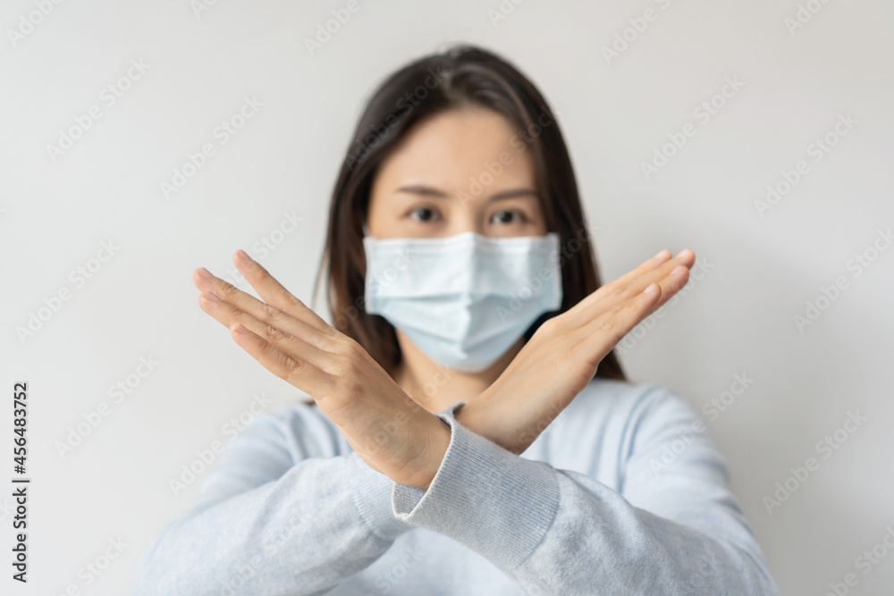 Stress young Asian woman wearing medical mask making X sign with crossed hands, gesturing stop or say no on white background. Copy space Stress young Asian woman wearing medical mask making X sign with crossed hands, gesturing stop or say no on white background. Copy space