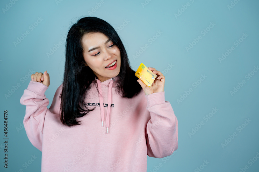 Portrait of an Asian girl wearing a pink shirt. in mobile credit card pose for a photo with happy expression, behind gray background in studio Portrait of an Asian girl wearing a pink shirt. in mobile credit card pose for a photo with happy expression, behind gray background in studio