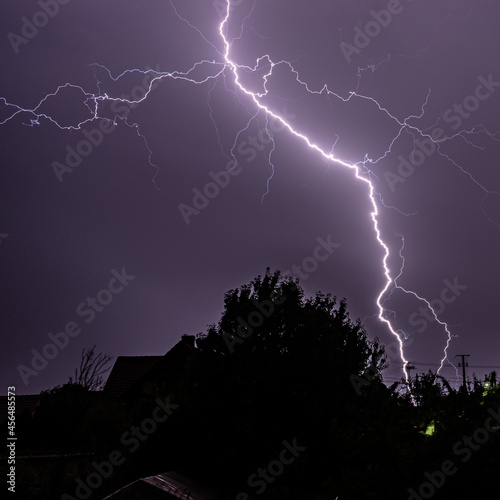 Lightning strikes painting the sky purple on a summer evening during a thunderstorm view from a window