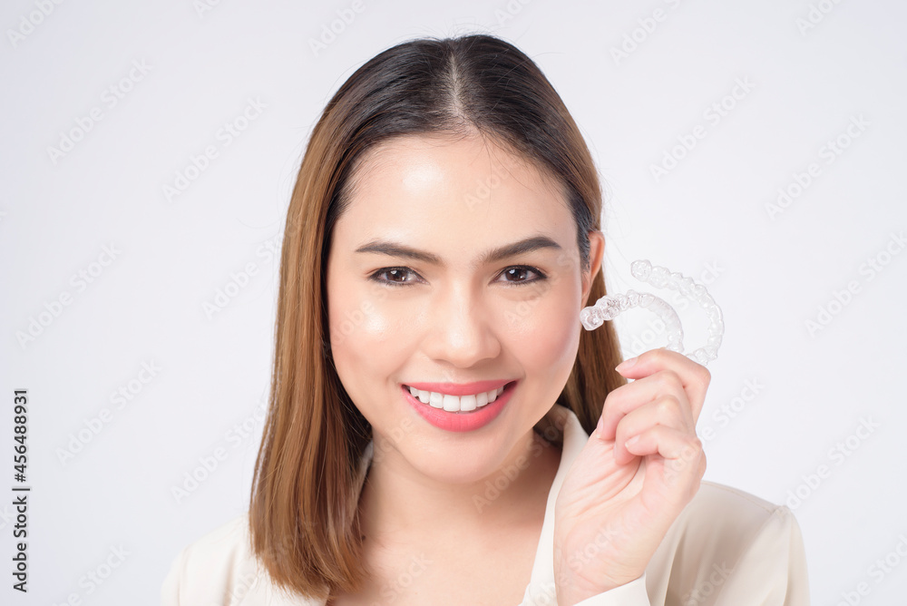 Young smiling woman holding invisalign braces in studio, dental healthcare and Orthodontic concept Young smiling woman holding invisalign braces in studio, dental healthcare and Orthodontic concept