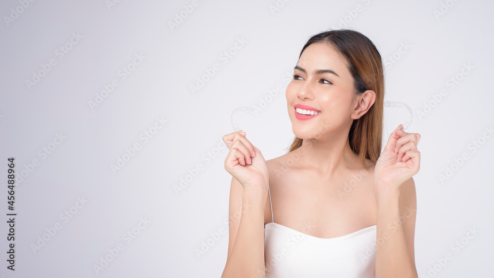 Young smiling woman holding invisalign braces in studio, dental healthcare and Orthodontic concept Young smiling woman holding invisalign braces in studio, dental healthcare and Orthodontic concept