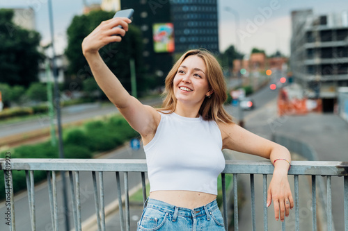 Young caucasian woman outdoor using smartphone taking selfie smiling happy