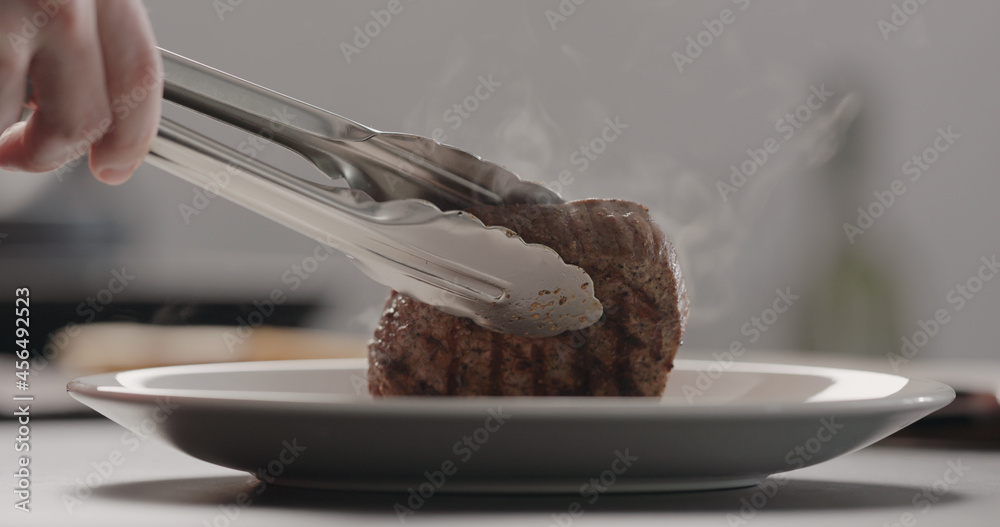 Fototapeta premium man put hot steak on white plate