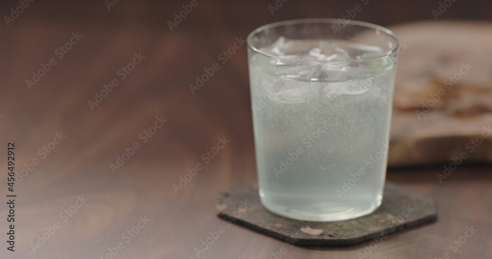 green sparkling drink in tumbler glass from walnut table