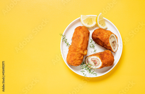 Canvas-taulu French traditional cuisine crispy, creamy chicken cordon bleu on yellow background