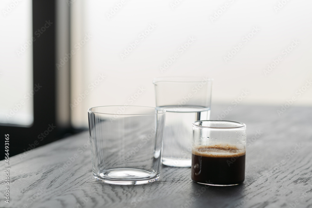 Ingredients for espresso tonic with clear ice cube in tumbler glass on oak wood table with copy space