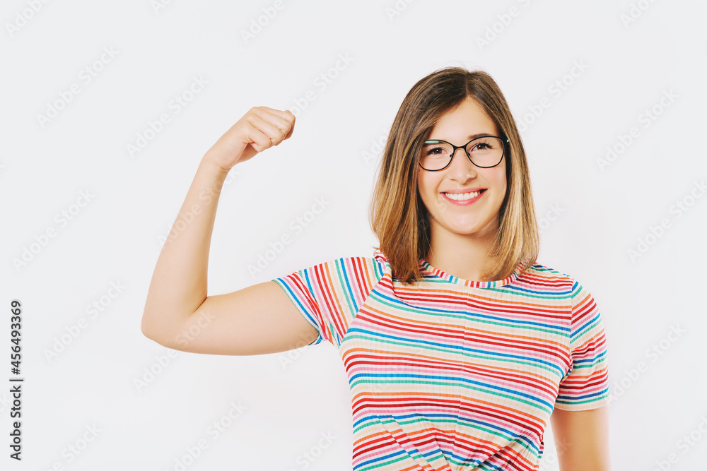 Studio portrait of young happy model showing how strong she is, wearing rainnbow t-shirt and glasses Studio portrait of young happy model showing how strong she is, wearing rainnbow t-shirt and glasses
