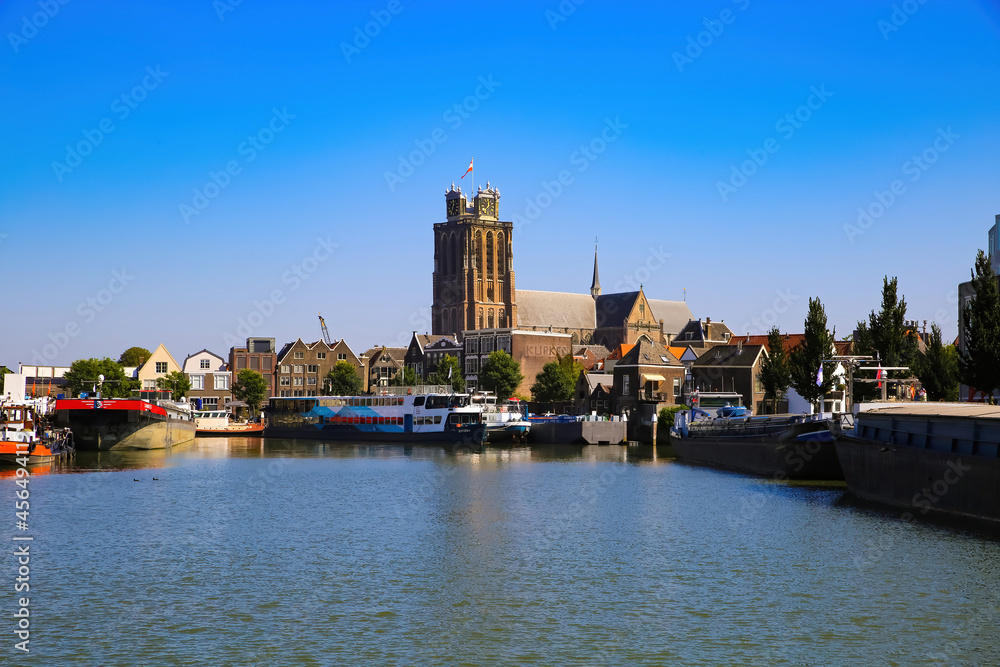 Dordrecht, Netherlands - July 9. 2021: View over dutch inland harbor on skyline of old town with church tower against blue summer sky
