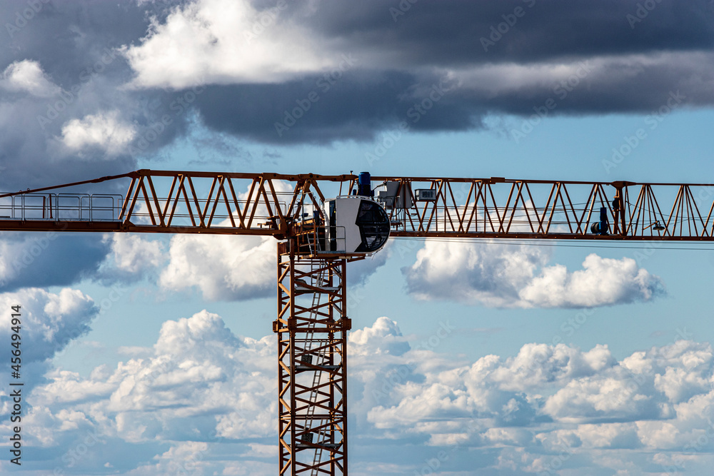 Tower crane close-up against the background of the cloudy sky. Shooting from a drone. Modern building technologies.