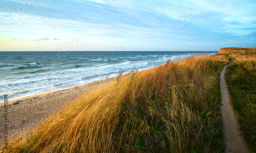 Photo of a seascape. Morning sea, sunrise, dunes and hills, beautiful coast and waves.