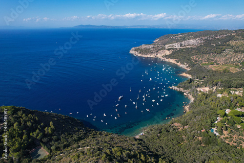 Fototapeta Naklejka Na Ścianę i Meble -  View from above, stunning aerial view of a bay with boats and luxury yachts sailing on a turquoise, clear water surrounded by cliffs. Porto Santo Stefano, Monte Argentario, Italy.