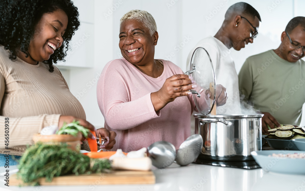 Happy African family having fun in modern kitchen preparing food recipe with fresh vegetables - Food and parents unity concept Happy African family having fun in modern kitchen preparing food recipe with fresh vegetables - Food and parents unity concept