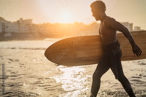 Afro surfer having fun surfing during sunset time - African man enjoying surf day - Extreme sport lifestyle people concept photo