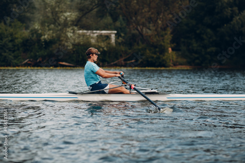 Sportsman single scull man rower rowing technique on boat. Paddle oar splash movement motion