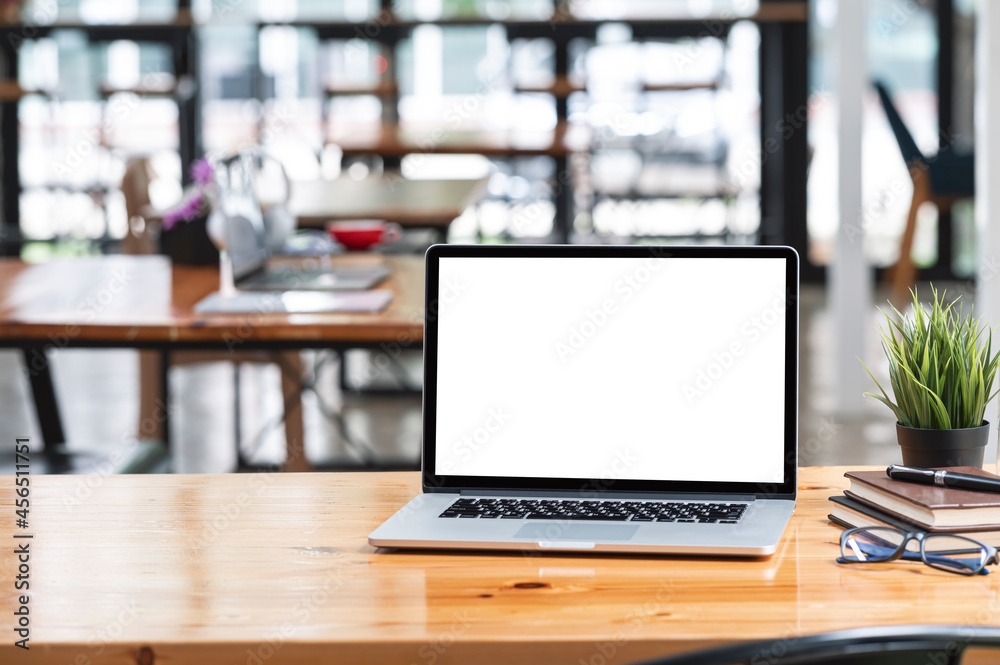 Blank screen laptop computer and supplies on wooden table in contemporary office room with copy space. Blank screen laptop computer and supplies on wooden table in contemporary office room with copy space.