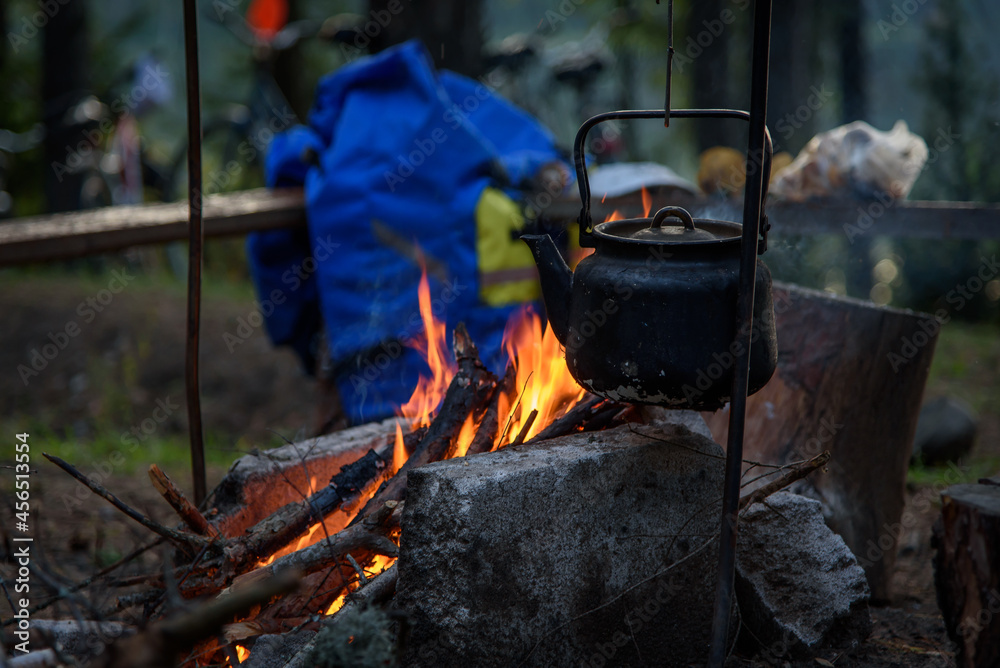 The kettle stands over a fire in the forest. A smoked kettle over the fire. The kettle stands over a fire in the forest. A smoked kettle over the fire.
