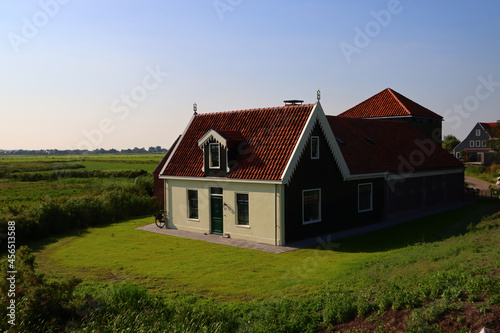 Dutch country house in a field, white walls, red tiled roof, green grass. Big house close up photo. Countryside landscape of the Netherlands. 