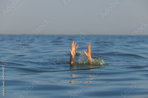 Drowning woman reaching for help in sea