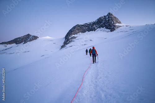 Climbers team on a trail through a dangerous glacier and avalanches in Austiran Alps. Route to the Grossvenediger rock summit, East Tyrol, National Park Hohe Tauern, Austrian Alps, Europe