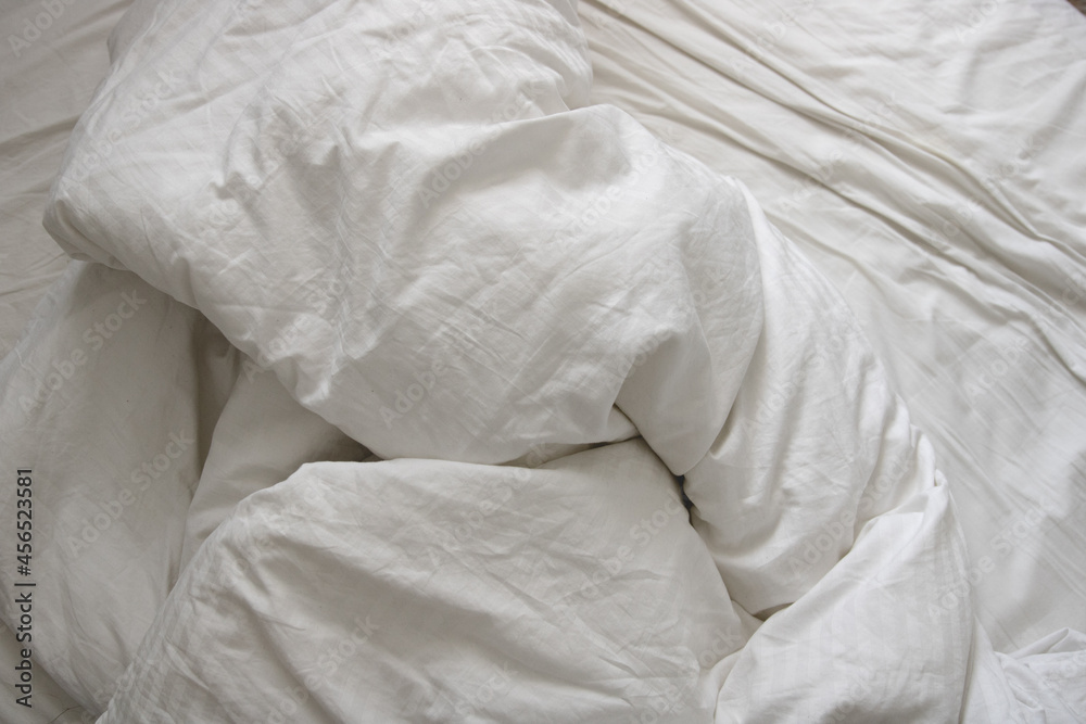 messy and crumpled  natural white bed sheets in bed - obrazy, fototapety, plakaty 