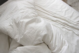 messy and crumpled natural white bed sheets in bed