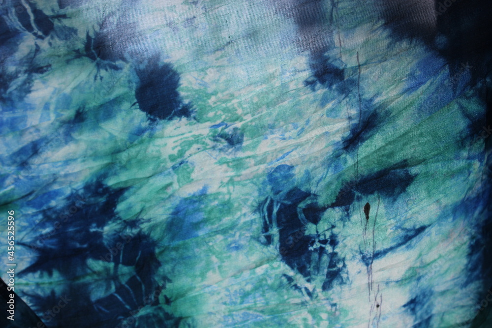 Tie dye green background with half circle layers of dye pattern fading from green to white dye fabric textile