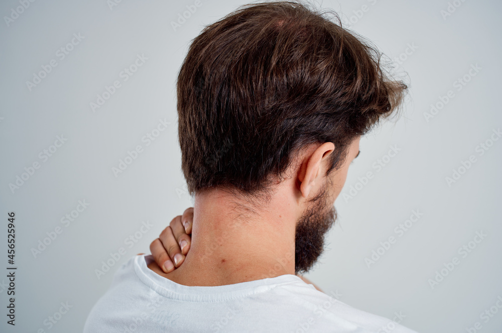 Obraz premium bearded man in a white t-shirt stress medicine pain in the neck studio treatment