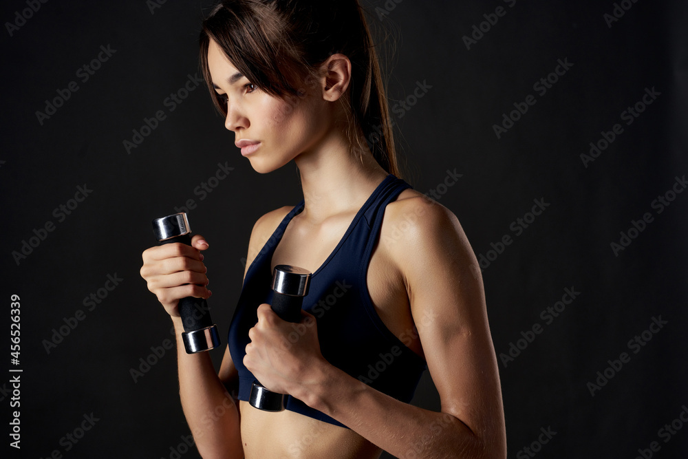 slender woman fitness exercise dumbbells in the hands of Strong studio gym slender woman fitness exercise dumbbells in the hands of Strong studio gym