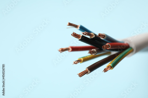 Many stripped electrical wires on light blue background, closeup