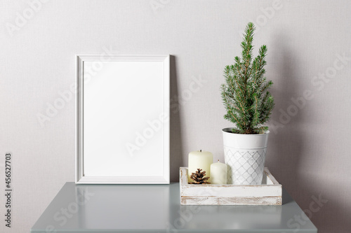 Fototapeta Naklejka Na Ścianę i Meble -  White blank frame mockup and wooden tray with potted Christmas tree, candles. Scandinavian home decor, nordic design. space for text.