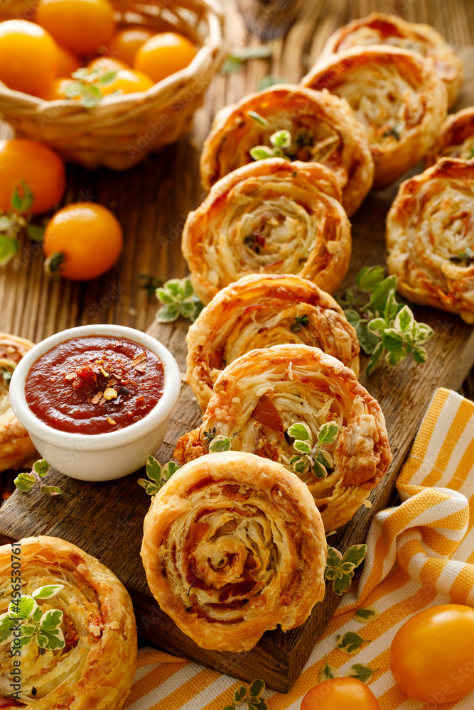 Bacon and cheese puff pastry pinwheel served on a board, top view. A delicious snack perfect for parties