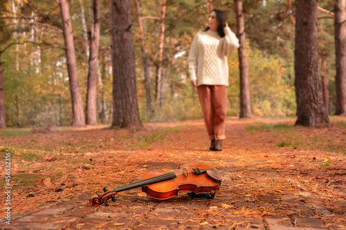 Violin Lying on Red and Orange Autumn Tree Leaves Background