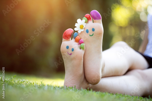 Children's feet with a pattern of paints smile on the green grass. © erika8213