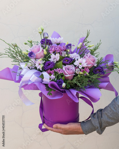 Foto Bouquet of flowers in purple hat box on a light background.