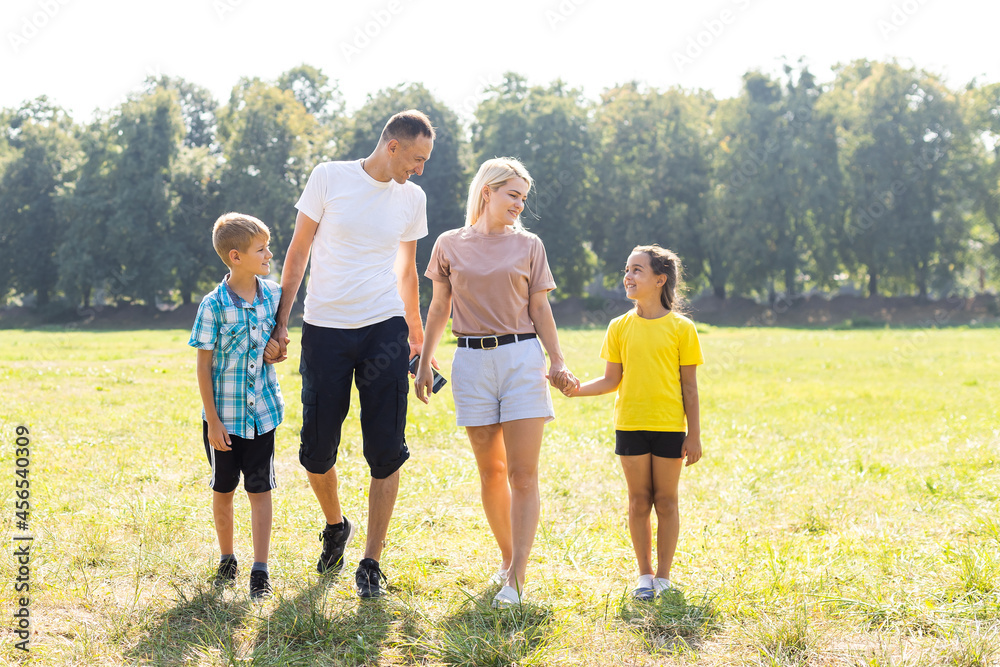 Happy loving family walking outdoor in the light of sunset. Father, mother, son and daughter.