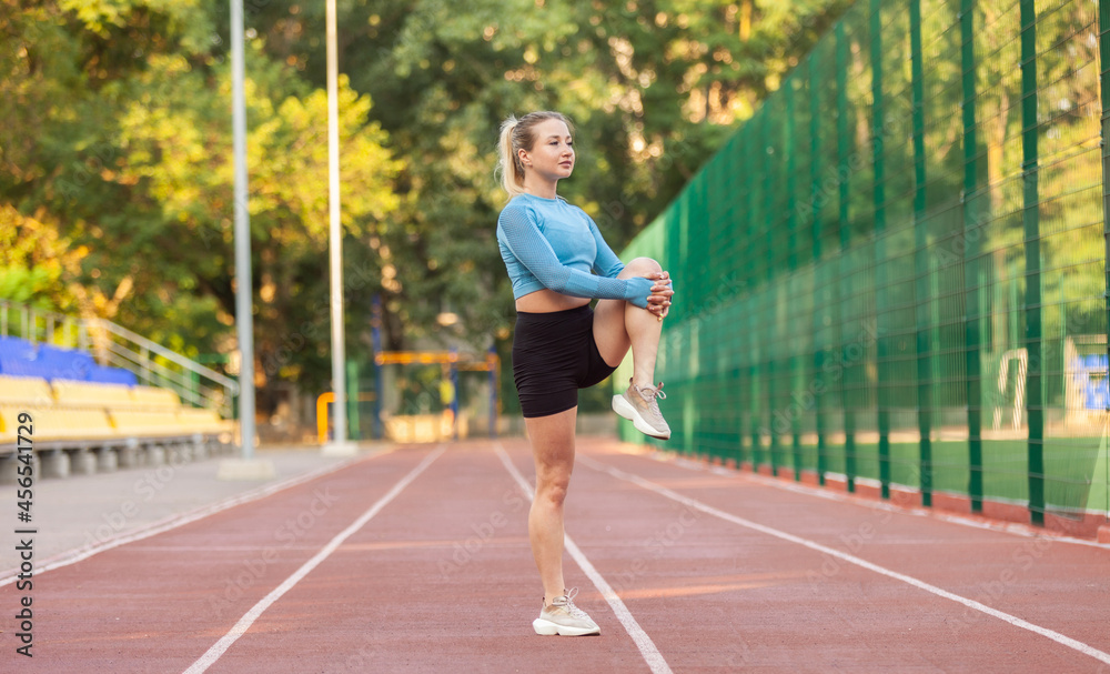 Young athletic woman practicing leg stretching in the stadium. Healthy lifestyle