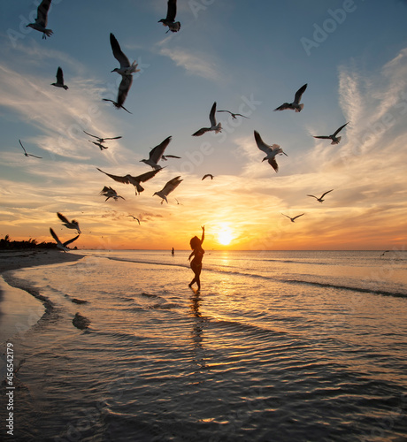 Silhouette of a woman dancing on a tropical beach at sunset with seagulls in flight, Holbox Island, Mexico © Marco B.