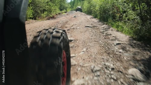 The front wheel of the buggy rides on a rocky road. Rear side view