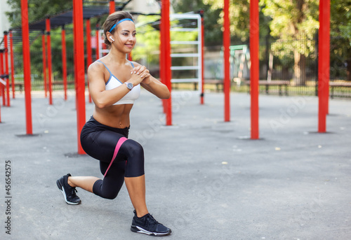 Young muscular woman trains muscles with fitness rubber bands on a sports workout ground. Healthy lifestyle. Fitness and bodybuilding. Resistance training © splitov27