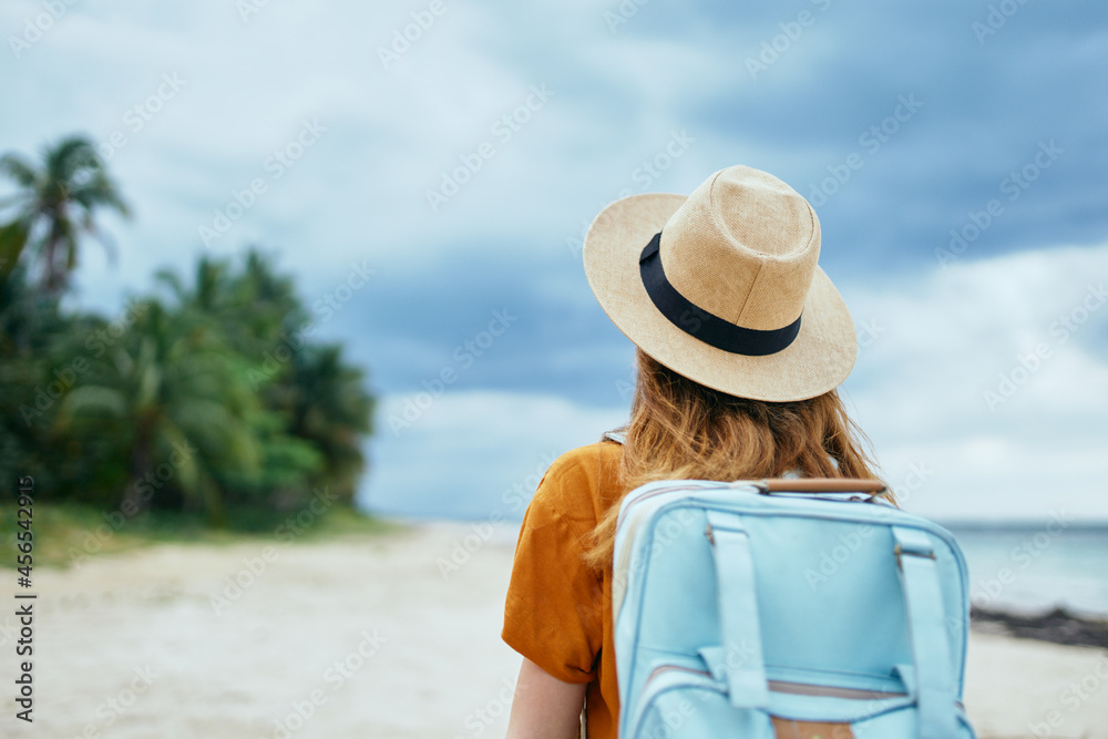 traveler with backpack hat on head and orange sundress tourism back view