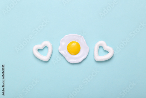 Bild auf Leinwand Plastic scrambled eggs with hearts on blue background