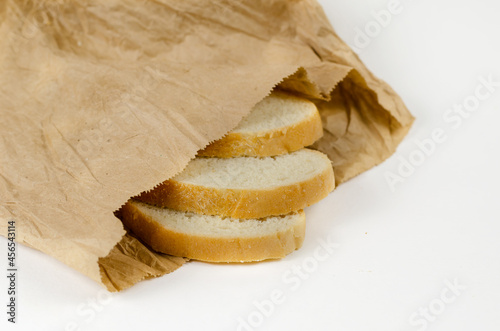 Slices of bread in a paper bag. Three slices of wheat bread in a brown lunch bag. White background.